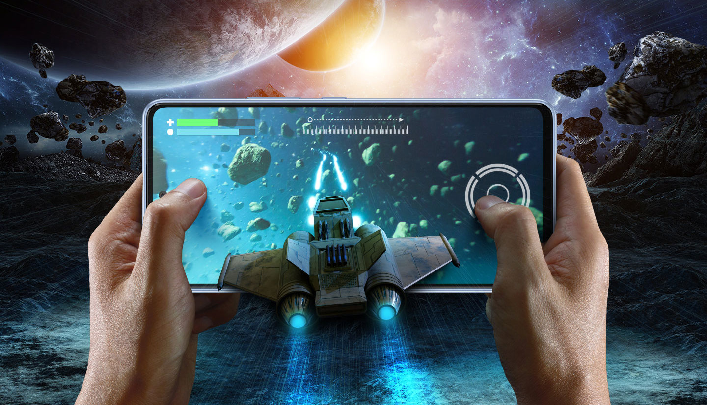 Two hands are shown holding the Galaxy A53 5G in landscape mode. On screen, a shooting game is being played where the player maneuvers a rocket ship in space. In between the hands and from outside the screen, a rocket ship is flying into the screen, shooting lasers that extend inside into the game. On the background, the landscape is set in space with various meteors and planets shown in the distance. Text above reads Temperature, Memory and Battery Time.