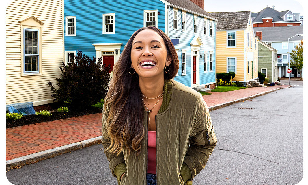 A woman is standing in front of colorful houses. With the Portrait Off icon above activated, the background is clear and portrays both the woman and the colorful houses accurately.