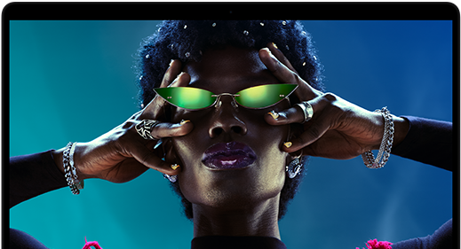 شاشة ملونة على MacBook Pro تُظهر شخصاً يتفاعل بحماس مع الجمهور في إحدى الحفلات، ما يبرز حيوية شاشة ريتنا ليكويد XDR النابضة بالحياة