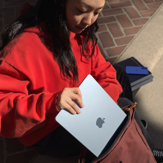 A student placing a 15" MacBook Air into their backpack